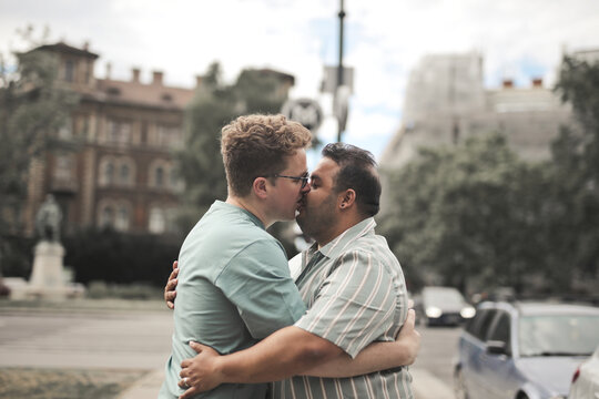 Interracial gay couple embracing and kissing outdoors