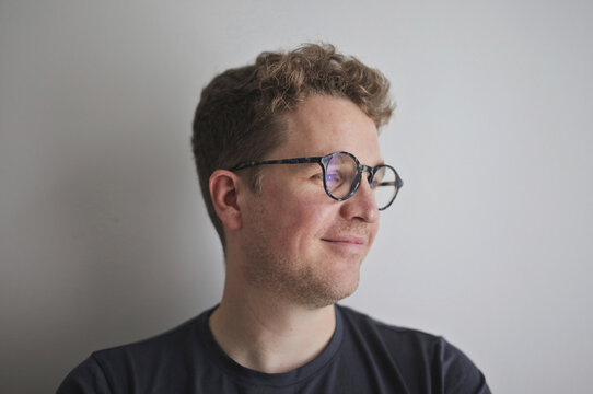Young man with curly hair and glasses smiling