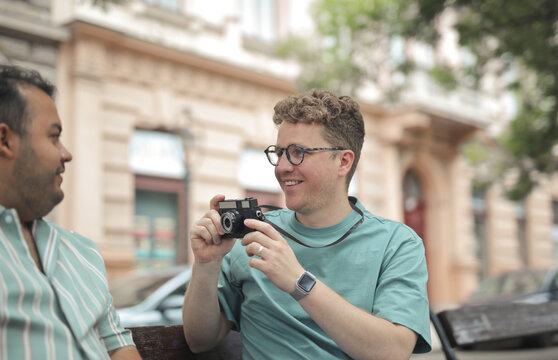 Smiling man with glasses photographs his friend