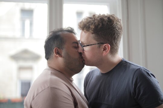 Two men sharing a romantic kiss indoors