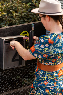 woman paying for produce at roadside stall using honesty box system putting cash in mailbox