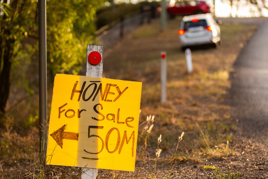 local honey for sale sign with arrow to roadside stall in Australia
