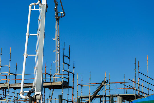 concrete pump machine pumping concrete over scaffolding into construction site