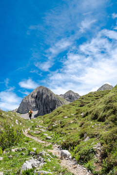 Hiker in the Alps mountains with the North face of Pizzo Petto on background, Orobie mountains, Lombardy