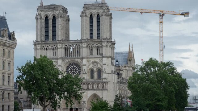 Notre Dame de Paris historic gothic cathedral facade stands near Seine river bridge in France. This famous religious landmark serves international travel industry and heritage media.
