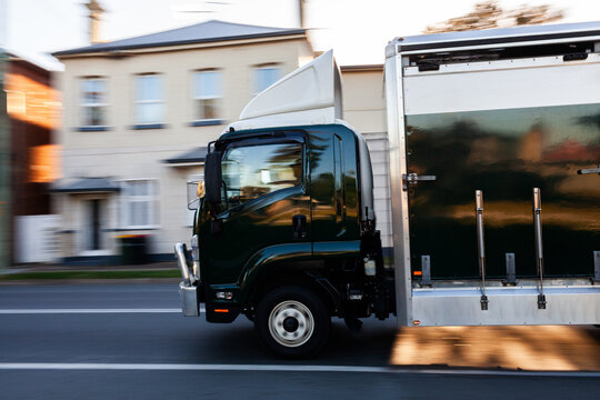 Panning image of truck driving past on country town road in sunrise light