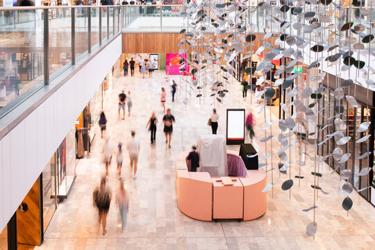 ground floor of large shopping centre, with retail stores, kiosk, blurred shoppers
