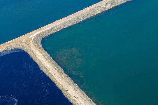 Reservoir with embankment dividing turquoise and deep blue water