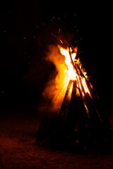 Tall teepee campfire glowing orange with smoke at dark night © Ionut Gaspar