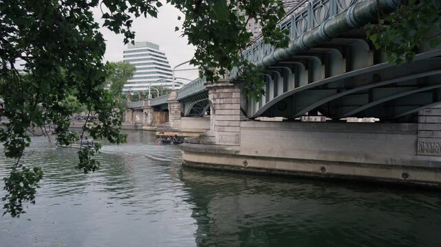 Bir-Hakeim bridge structure stands over River Seine with small motorboat floating in Paris France. Transport architecture landmark serves for travel guidebook planner and city navigation.