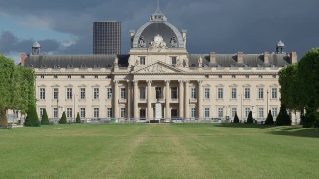 Ecole Militaire historic building facade with green grass lawn field under cloudy stormy sky in Paris France French military academy architecture landmark heritage travel tourism concept.