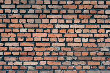 Fototapeta premium Detailed close up surface of a rugged vintage brick wall, loft style backdrop. Old terracotta brickwork pattern, grunge architectural background.