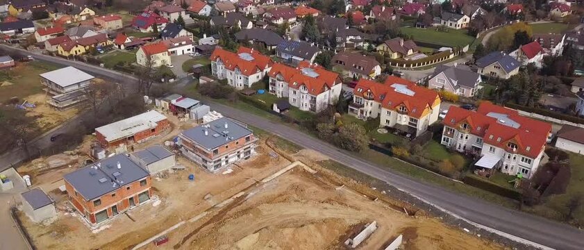 Aerial view of suburban neighborhood showing new modern houses currently under active construction near existing residential homes