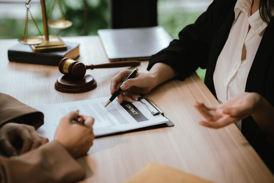 Close-up of a legal consultation and contract review, with professionals discussing agreement terms, signing documents, and legal compliance in an office setting.