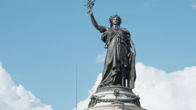 Marianne statue monument stands at Place de la Republique in Paris France. French republic national symbol woman holds an olive branch representing democracy, freedom and patriotic history.