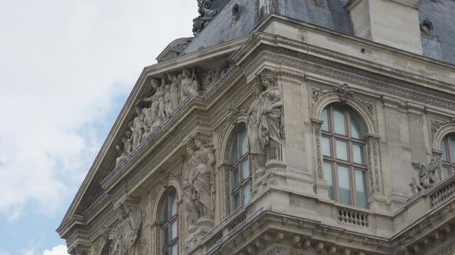 Louvre museum palace facade features historical French architecture with stone statues, classical columns and relief sculptures. European landmark exterior represents tourism travel trip.