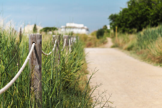 Nature trail with wooden rope fence in Les Madrigueres wetland reserve, shallow depth of field highlighting protected landscape and visitor pathway