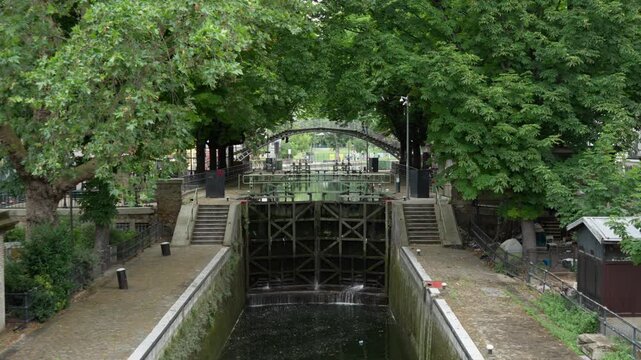 Canal lock gate system controls water level on Saint-Martin canal in Paris France for urban river transport shipping infrastructure and European historical heritage travel tourism industry.