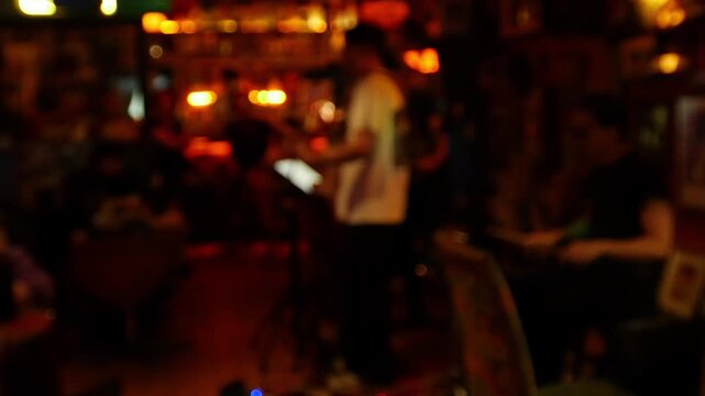 Blurred defocused live music band performance inside dark moody bar with warm amber bokeh lights and crowd audience nightlife