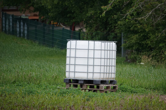 Ein IBC-Container mit einem Fassungsverm&ouml;gen von 1000 Litern auf einer Palette mitten auf einer Wiese