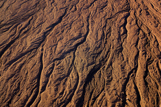 Aerial view of the arid, textured landscape of the Atacama Desert with deep erosion channels and dry earth patterns in Antofagasta, Antofagasta, Chile.