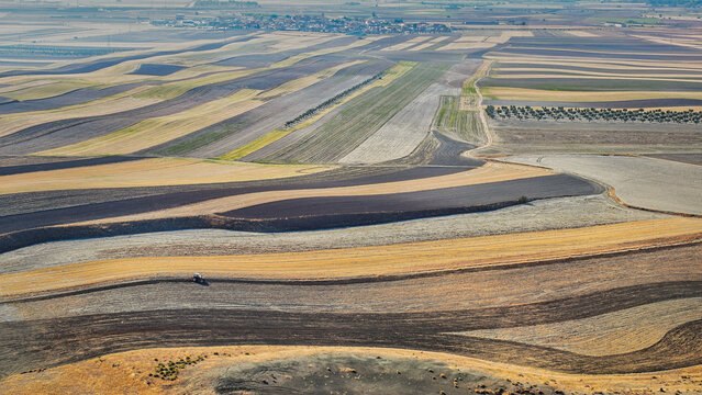 Panoramic elevated view of fallow cereal fields in La Sagra, Toledo, Spain, with dark plots fertilized with wastewater treatment sludge.