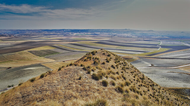 Panoramic elevated view of fallow cereal fields in La Sagra, Toledo, Spain, with dark plots fertilized with wastewater treatment sludge.