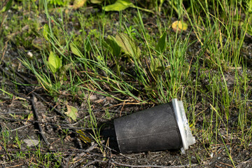 Fototapeta premium Abandoned Coffee Cup Discovered on the Ground Surrounded by Lush Green Grass and Natural Vegetation in a Quiet Outdoor Setting