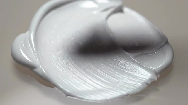 Smooth white paint texture being spread with a spatula on a neutral surface close up