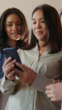 Vertical video: Holding phone center woman beige top tapping screen at home sharing with friends