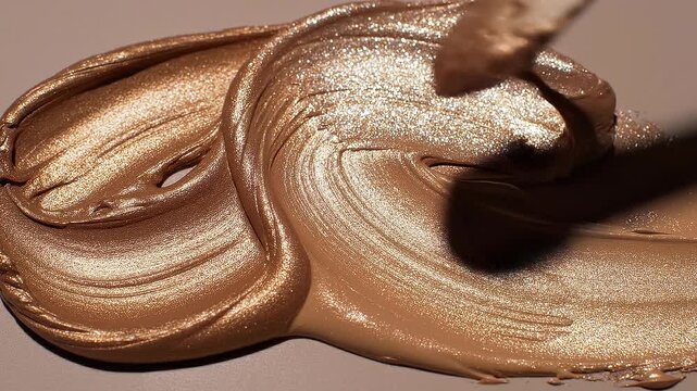 Close up of shimmering golden liquid makeup foundation texture with smooth creamy finish