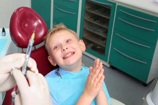 Little boy is very afraid of injection. Childish fear. Syringe is in doctor's hands. Dentist's appointment. Negative emotions