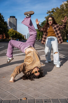 Gen-Z female street dancers doing breakdance on city road