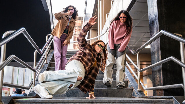 Gen-Z women friends doing street dance on urban stair