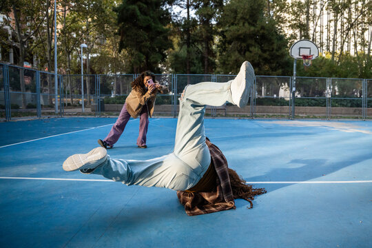 Gen-Z female breakdancer on outdoor court with photographer