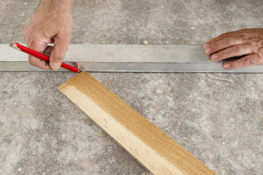 Worker hands measuring and marking layout for Italian herringbone parquet flooring installation