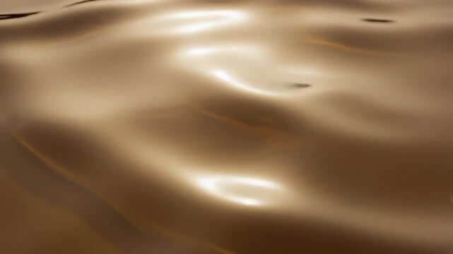 Close up of smooth flowing golden liquid surface with warm reflections and soft highlights