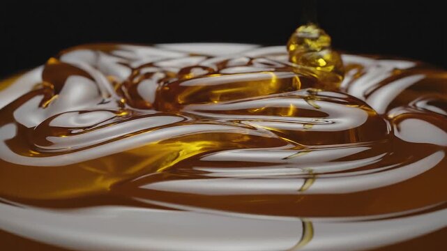 Close up of golden honey pouring and swirling with smooth texture on dark background