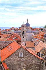 Obraz premium Aerial and above view of Dubrovnik old town with the Bell and Clock Tower and the red orange tiled roof surrounded by the city wall, Croatia 