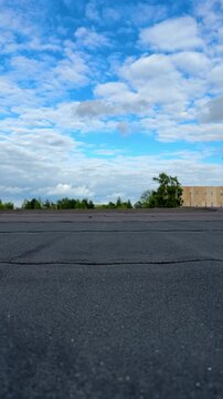 Bottom view of black bitumen membrane of flat roof under blue cloudy sky, background for waterproof roofing construction