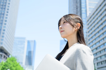 Fototapeta premium ビル街でノートパソコンを使う日本人女性