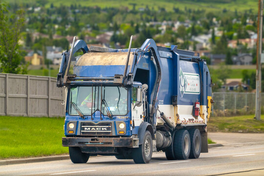Calgary, Alberta, Canada. June 20, 2026. Front view of a blue Mack garbage truck driving on a city road.
