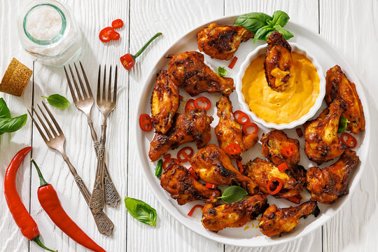 Char-grilled chicken wings on a plate with sauce