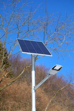 Modern solar powered street lamp with photovoltaic panel under blue sky