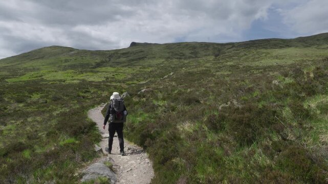 Hiker with big backpack walking up the Devil's Staircase on the West Highland Way in Scotland.