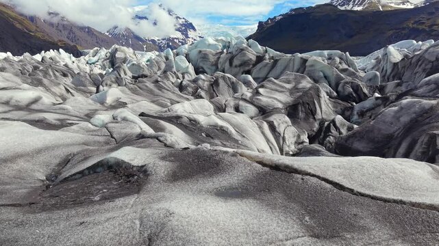 Majestic aerial view of the Svinafellsjokull glacier tongue extending from the Vatnajokull ice cap. Its surface shows black volcanic ash