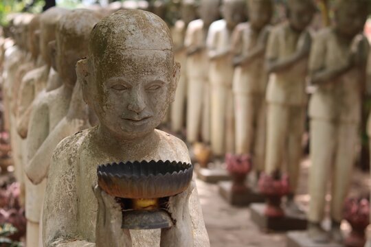 Ancient Stone Buddhist Monk Statues Holding Alms Bowls in a Row Along Temple Path at Prasat Vimean Koh Pos Kien Svay Cambodia