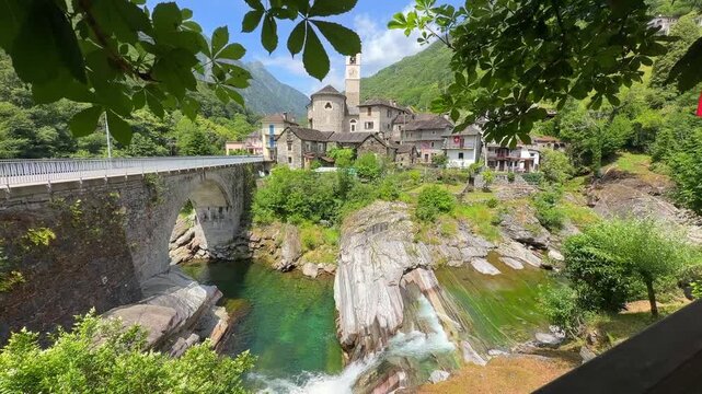 Scenic view of Lavertezzo village in Switzerland featuring the iconic Ponte dei Salti stone bridge spanning the emerald waters of the Verzasca River 