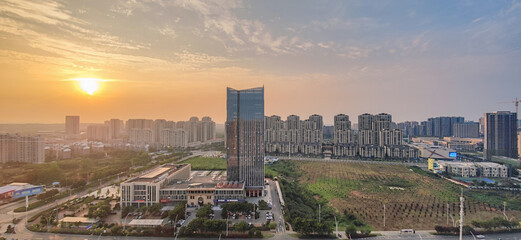 Panoramic cityscape at golden sunset, new urban district with modern high-rise buildings and farmland © dongyu