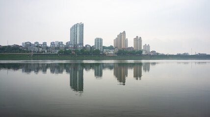 Calm lake reflecting city high-rise buildings at sunset © dongyu